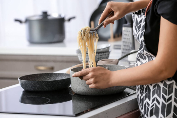 Woman cooking tasty pasta in kitchen - Foto, Imagem