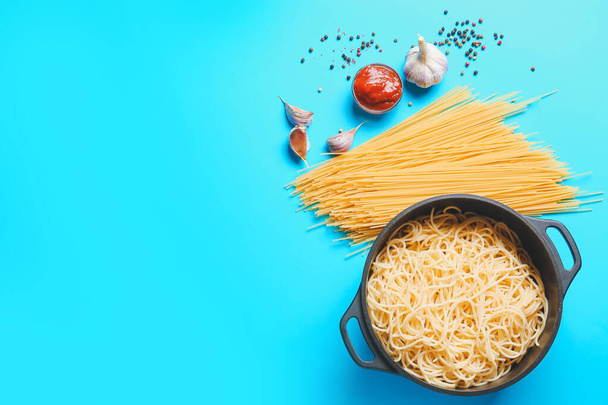 Cooking pot with pasta and ingredients on color background - Photo, Image