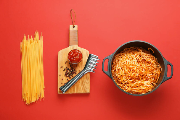 Cooking pot with pasta and ingredients on color background - Photo, image