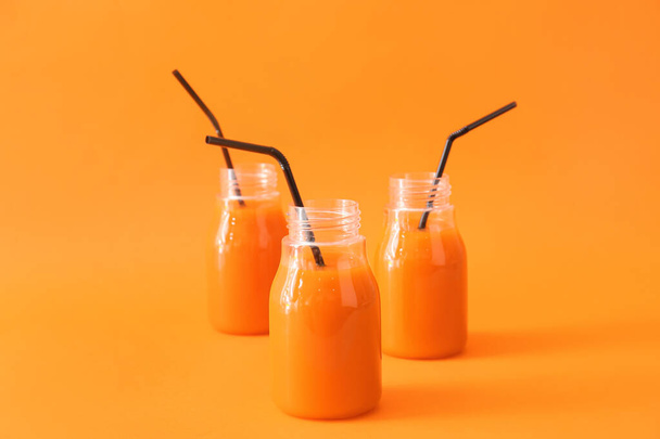 Flaschen mit gesundem Karottensaft auf farbigem Hintergrund - Foto, Bild