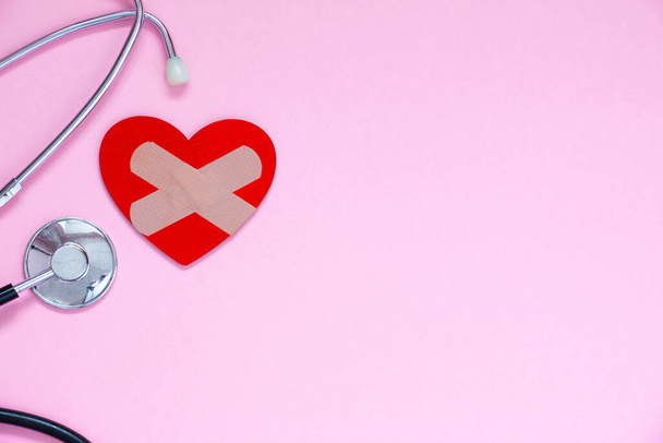 Orvosi sztetoszkóp és vörös szív gipsszel bekötve. Egészségügyi Világnap koncepció Medical Banner Template Copy Space - Fotó, kép