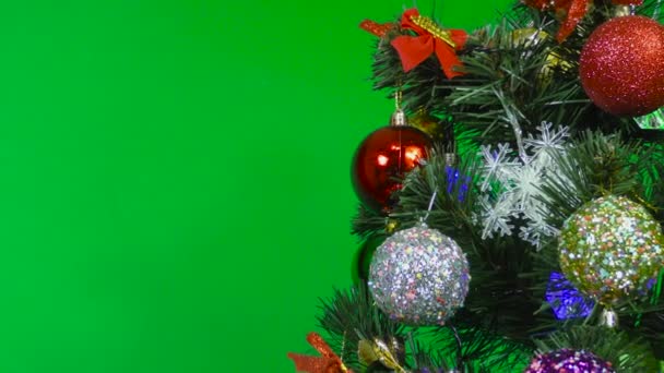 Σε ένα πράσινο φόντο κοντά σε ένα χριστουγεννιάτικο δέντρο πολύχρωμες διακοσμήσεις - Πλάνα, βίντεο