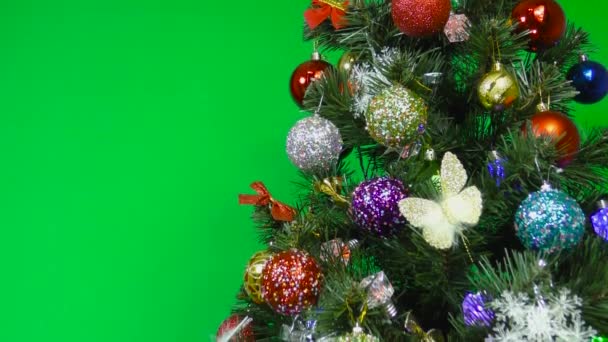 Árbol de Navidad decorado con decoraciones navideñas sobre un fondo verde - Metraje, vídeo