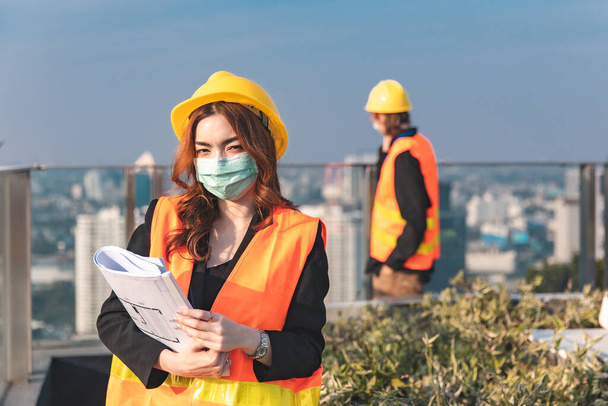 Engineers in mechanical factory reading instructions.smiling manufacture worker  man and woman stand confident with the background of white sky and building tower. Concept of industry building people with art flare background. - Foto, Imagen