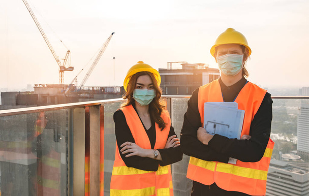 Engineers in mechanical factory reading instructions.smiling manufacture worker  man and woman stand confident with the background of white sky and building tower. Concept of industry building people with art flare background. - Foto, Imagen