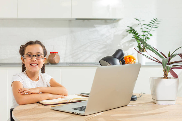 Foto von positiven Kind Mädchen Studie Remote Sit Schreibtisch Tisch verwenden Laptop haben Online-Kommunikationsunterricht mit Tutor Bericht schreiben im Haus drinnen - Foto, Bild