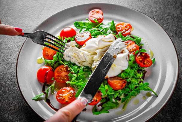 woman eating healthy salad with burrata cheese, arugula salad and tomatoes - Photo, image