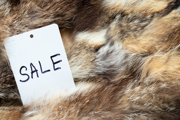 έκπτωση γραμμένο σε μια λευκή ετικέτα τιμή που βρίσκεται σε ένα φόντο γούνα, η τιμή της γούνας - Φωτογραφία, εικόνα