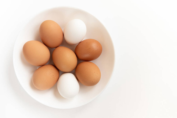 Group of fresh eggs. Brown chicken eggs, isolated on white background. Preparation for painting Easter eggs. Top view - 写真・画像