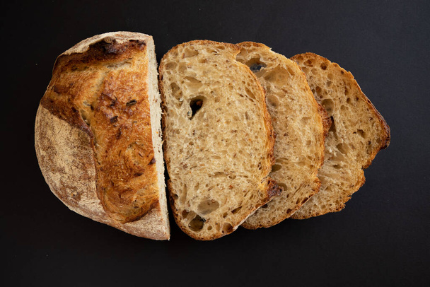 Pane integrale fresco a fette su fondo nero. Fette di pane a fette. Vista dall'alto. - Foto, immagini
