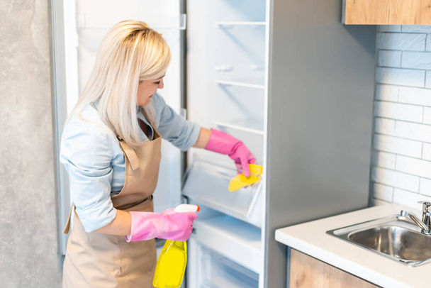Jeune femme nettoyage armoires de cuisine - Photo, image