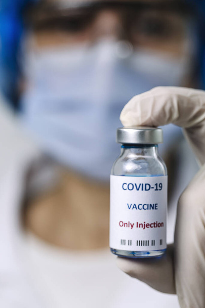 COVID-19 vaccine in researcher hands, unrecognizable female doctor holds syringe and bottle with vaccine for coronavirus cure. Concept of corona virus treatment - Foto, afbeelding