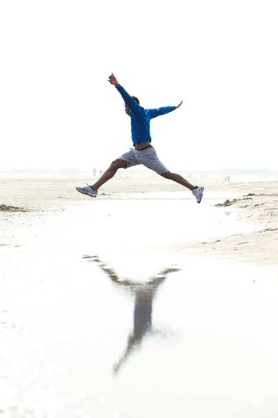 Mies juoksee ja hyppii rannalla
 - Valokuva, kuva