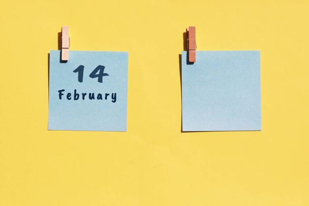 Le 14 février. 14e jour du mois, date du calendrier. Deux draps bleus pour écrire sur un fond jaune. Vue du dessus, espace de copie. Mois d'hiver, concept de jour de l'année - Photo, image
