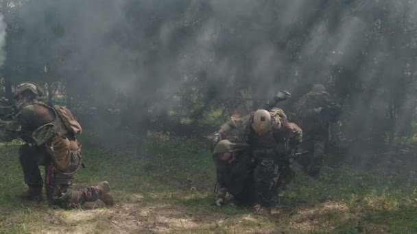 Imágenes de soldados arrastrando a su amigo herido a lo largo del campo de batalla ahumado, salvándolo aplicando torniquete a su pierna - Imágenes, Vídeo