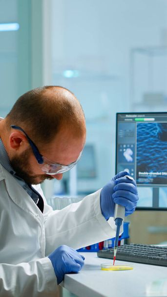 Wissenschaftler mit Mikropipette zum Befüllen von Reagenzgläsern in modern ausgestattetem Labor - Foto, Bild