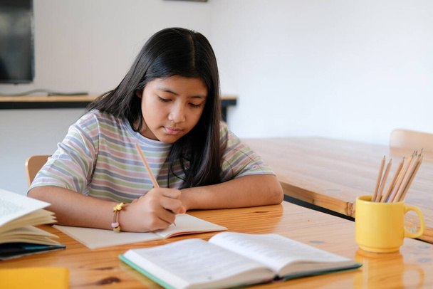 menina asiática estudante estudando escrever notas fazendo lição de casa na biblioteca. aprendizagem da educação na escola - Foto, Imagem