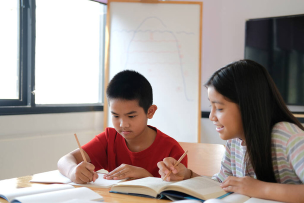asiatique garçon fille étudiant étudiant écriture notes faire devoirs dans bibliothèque. l'apprentissage à l'école - Photo, image