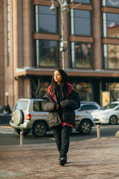 Street reportage photo of a woman in fashionable oversize clothes on a city street, looking away. Lady in fashionable clothes at fashion week walks down the street. - 写真・画像