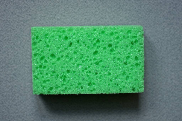 une éponge en mousse verte posée sur une table grise - Photo, image