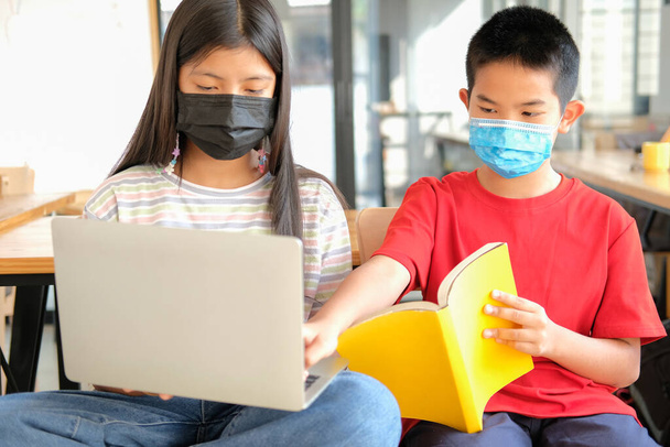 aziatische jongen meisje student dragen gezichtsmasker studeren les online. afstandsonderwijs op afstand thuis - Foto, afbeelding