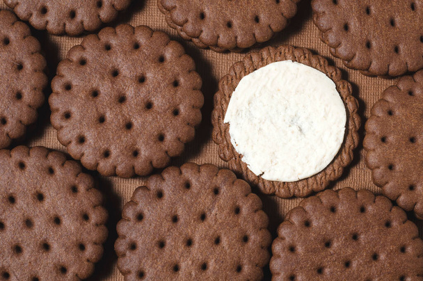 Texture background of rows of chocolate-cream cookies. One cookie with white buttercream. - Foto, immagini