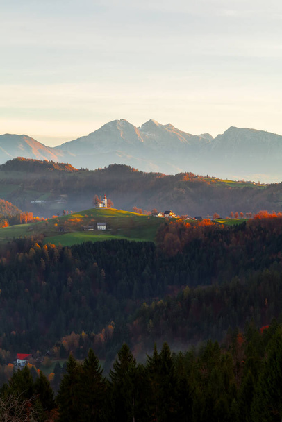 Kościół św. Tomasza (św. Tomasza) na wzgórzu o pięknym wschodzie słońca jesienią, w pobliżu Skofja Loka w regionie Górna Carniola w Słowenii - Zdjęcie, obraz
