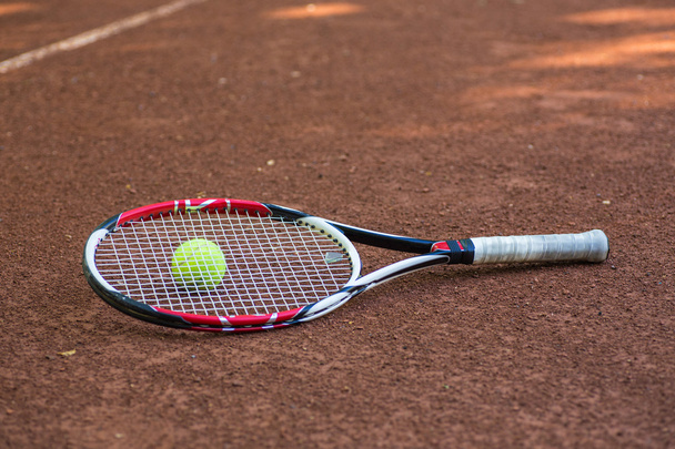 Raqueta de tenis y pelotas en la cancha de barro
 - Foto, Imagen