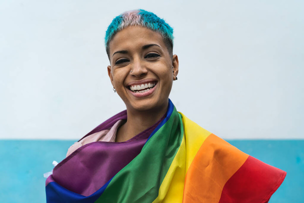 若い活動家の女性の笑顔とLgbtq社会運動の虹の旗のシンボルを保持 - 写真・画像