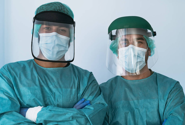 Врачи, носящие средства индивидуальной защиты от вспышки коронного вируса - концепция здравоохранения и медицинских работников - Фото, изображение