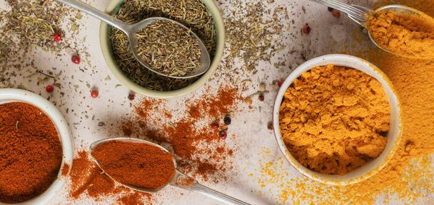 Various spices and seasonings: turmeric, paprika and provencal herbs on light brown stone background. Cooking background and copy space for text, top view. - Fotografie, Obrázek