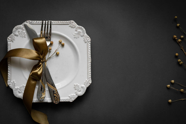 Концепция питания - черная тарелка с крестовым ножом, ложка на темно-коричневом столе - Фото, изображение