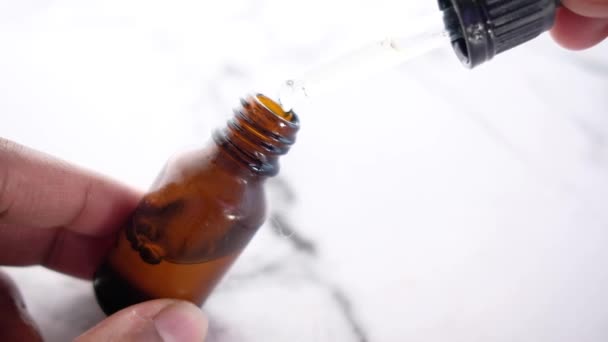 La goccia cade da una pipetta in una bottiglia cosmetica - Filmati, video