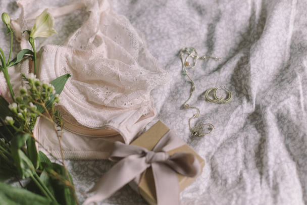 Happy Women's day. Stylish lace lingerie, gift box, modern jewelry and spring bouquet on bed. Soft trendy feminine image, sensual mood at home concept. Woman essentials - Fotografie, Obrázek