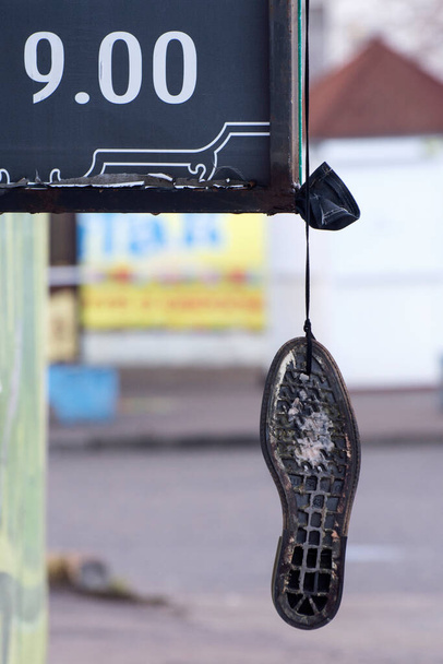 Old shoe soles hang at the entrance. Shoe repair shop sign. - Photo, Image
