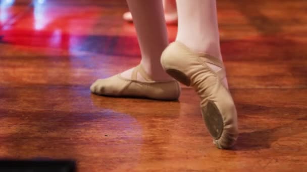 Kilátás a lába egy lány balett táncos a balett cipő edzés egy fa színpadon. Ismétlődő balettlépések. - Felvétel, videó