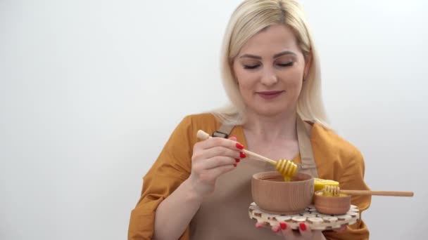 glimlachende jonge vrouw met schaal van honing op witte achtergrond - Video