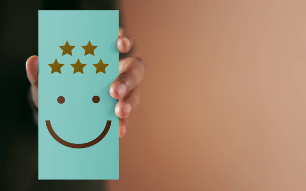 Customer Experience Concept. Happy Client giving Positive Review on Paper Card. Feedback a Happy Face Icon and Five Star Rating . Client's Satisfaction Surveys. Marketing Strategy - Photo, Image