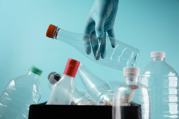 Kézzel tisztító kesztyű Dobás egy használt műanyag palack a kukába. Újrahasználat, újrahasznosítás és nulla hulladék kampány koncepció. Környezetvédelem - Fotó, kép