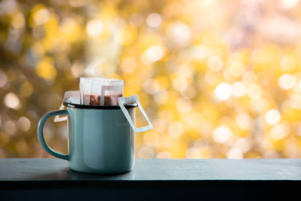 Капающий кофе на открытом воздухе утром. Делать горячий напиток с помощью мгновенного кофе капельной мешок. Уютная жизнь - Фото, изображение