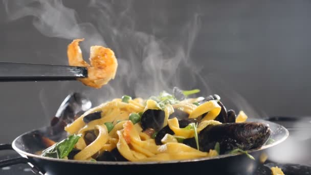 Podáváme lahodné smažené krevety s domácími špagetovými nudlemi těstovin. Zpomal. Tradiční těstoviny z mořských plodů s krevetami. Pára nebo stoupající pára. Tradiční italská kuchyně. Full hd - Záběry, video