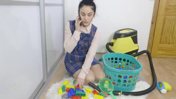 vrouw praten over de telefoon en het oppakken van speelgoed - Video