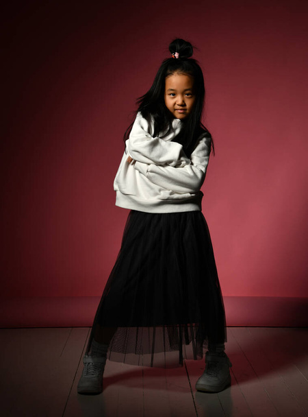 Fashion portrait of a little Korean model girl posing professionally on a red background. - Фото, зображення