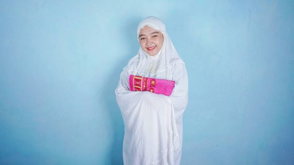Aasialainen nainen seisoo ja yllään muslimi hijab huivi mukena eristetty sinisellä taustalla - Ramadan / Ied Mubarak Concept - Valokuva, kuva