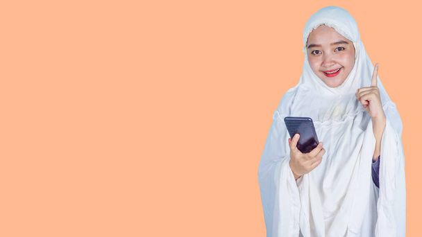 Feliz asiática hijab mujer en tener idea y mirando a la cámara sobre fondo brillante. Concepto de Ramadán - Foto, imagen