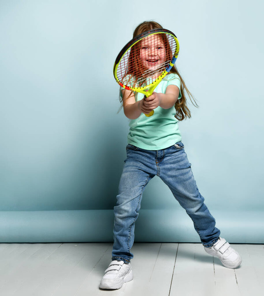 Little red-haired girl child playing big tennis studio shot - Foto, imagen