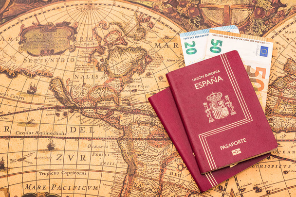 Passaporto spagnolo con banconote in euro all'interno, su una mappa del mondo per i viaggiatori. - Foto, immagini