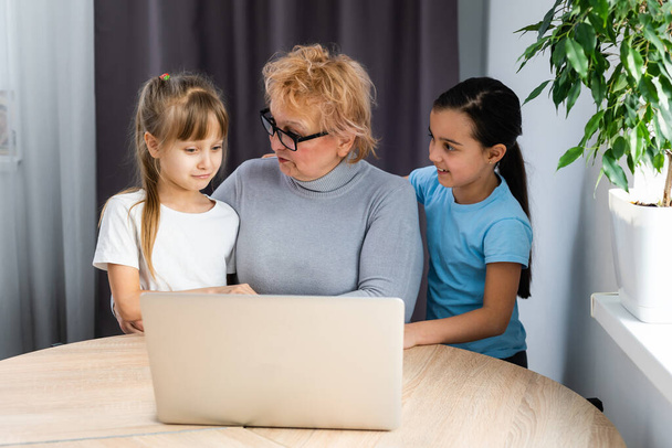 Großmutter und zwei Enkelinnen nutzen Laptop zu Hause - Foto, Bild