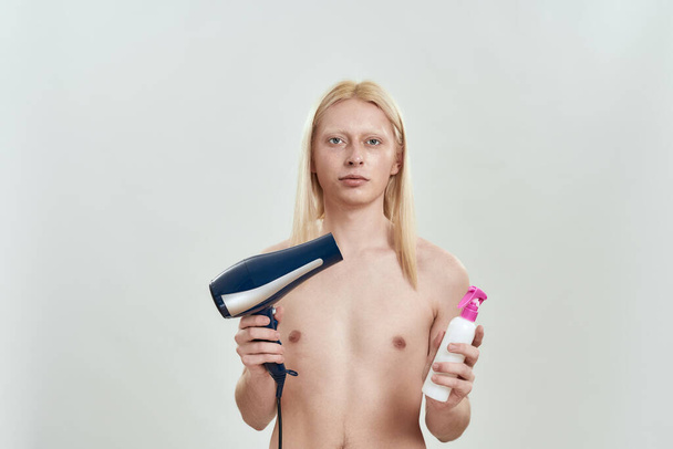 Young caucasian blonde man holding hair dryer - Foto, Imagem