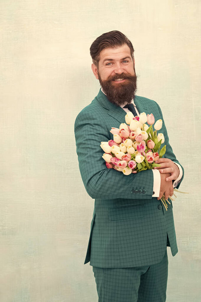 Womens day. March 8. Spring gift. Bearded man hipster with flowers. Celebrate spring. Making surprise. Gentleman with tulips. Spring is coming. Greetings. Bearded man with tulip bouquet. Love date - 写真・画像